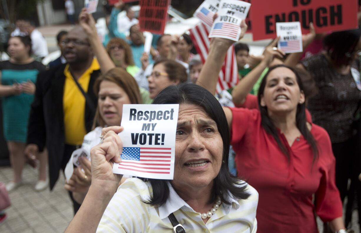 Photos by J Pat Carter/Associated Press
A child of a same-sex couple sits next to a protest sign, at left, and anti-gay-marriage protesters rally July 2 during a hearing on gay marriage in Miami. Fourteen religious leaders asked President Obama to exempt religious organizations when barring federal contractors from discriminating against gays in hiring; more than 100 have asked him not to.