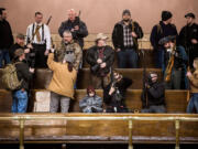 Demonstrators with weapons file into the pews of the House Gallery on Thursday to demand support to reverse Initiative 594 during a rally in the Capitol building in Olympia. The lieutenant governor announced Friday that open carry of guns has been banned in the Senate's public viewing area. No decision has been made on openly carrying guns in the House's public gallery.