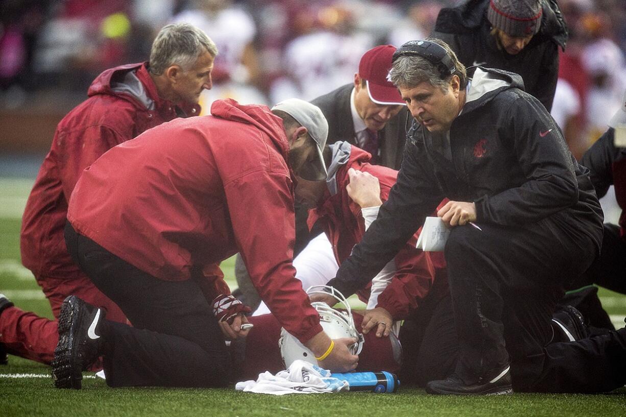 Washington State head coach Mike Leach comforts quarterback Connor Halliday, center, as team physicians and trainers attend him during the first quarter of an NCAA college football game Saturday, Nov. 1, 2014, at Martin Stadium in Pullman. Leach said Monday that Halliday suffered a broken ankle, ending his college career.