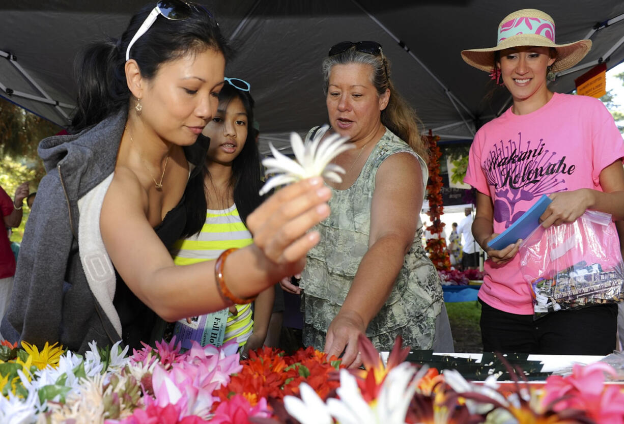 Kalei Sukhabut, left, choses a pua for her daughter Sydney, with the help of Kuulei Gumapac, center, at the Hawaiian festival in Esther Short Park in Vancouver, Wa., Saturday July 27, 2013.