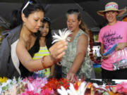 Kalei Sukhabut, left, choses a pua for her daughter Sydney, with the help of Kuulei Gumapac, center, at the Hawaiian festival in Esther Short Park in Vancouver, Wa., Saturday July 27, 2013.