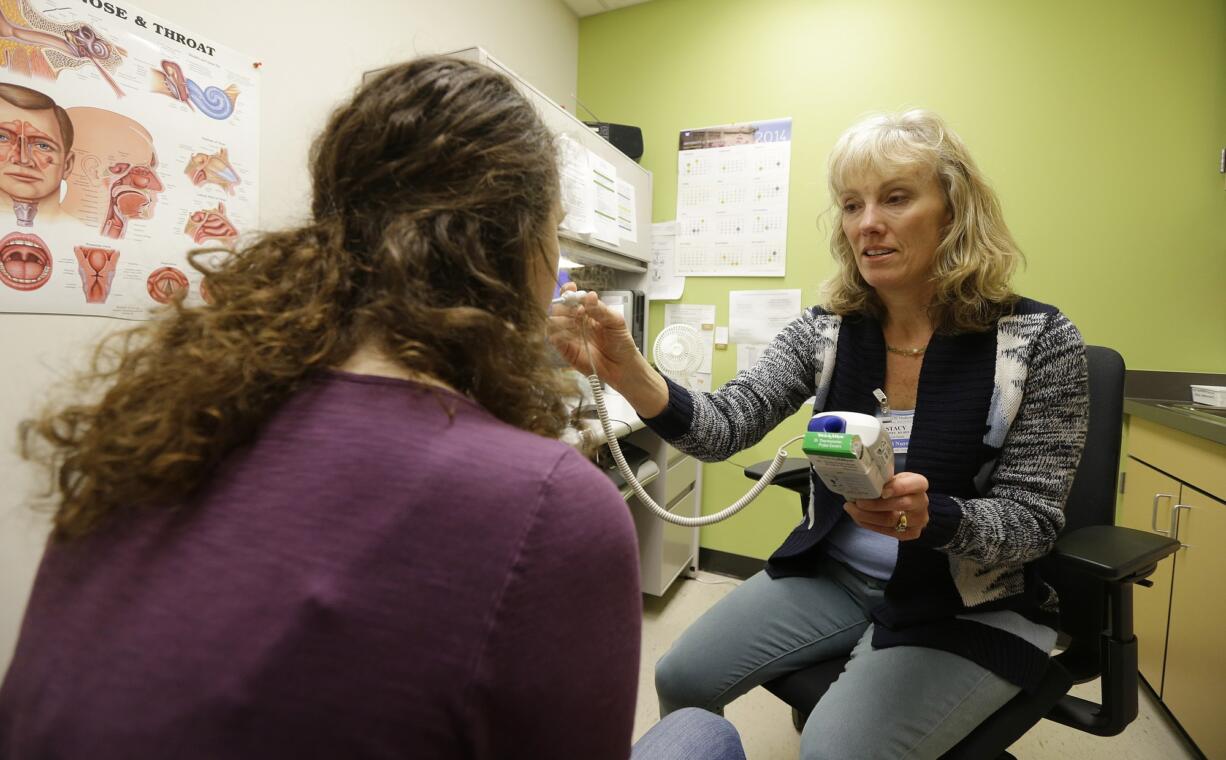 Stacy Crites, right, a nurse at the University of Washington's on-campus Hall Health Primary Care Center in Seattle, takes the temperature of archaeology junior Kandice Joyner during a routine check-up in December 2014.