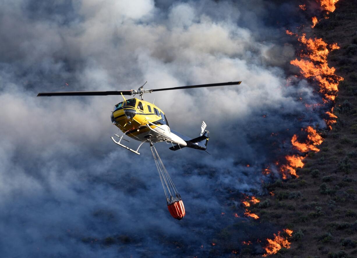 Emergency responders dump water onto a wildfire Saturday near Celebration Park south of Melba, Idaho.