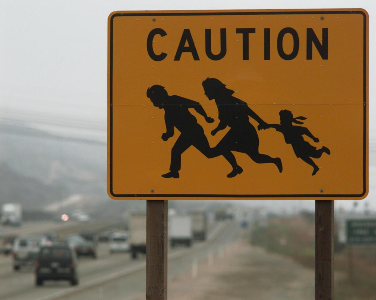 A sign warns motorists of the possibility of undocumented immigrants crossing the freeway near the border in San Diego.
