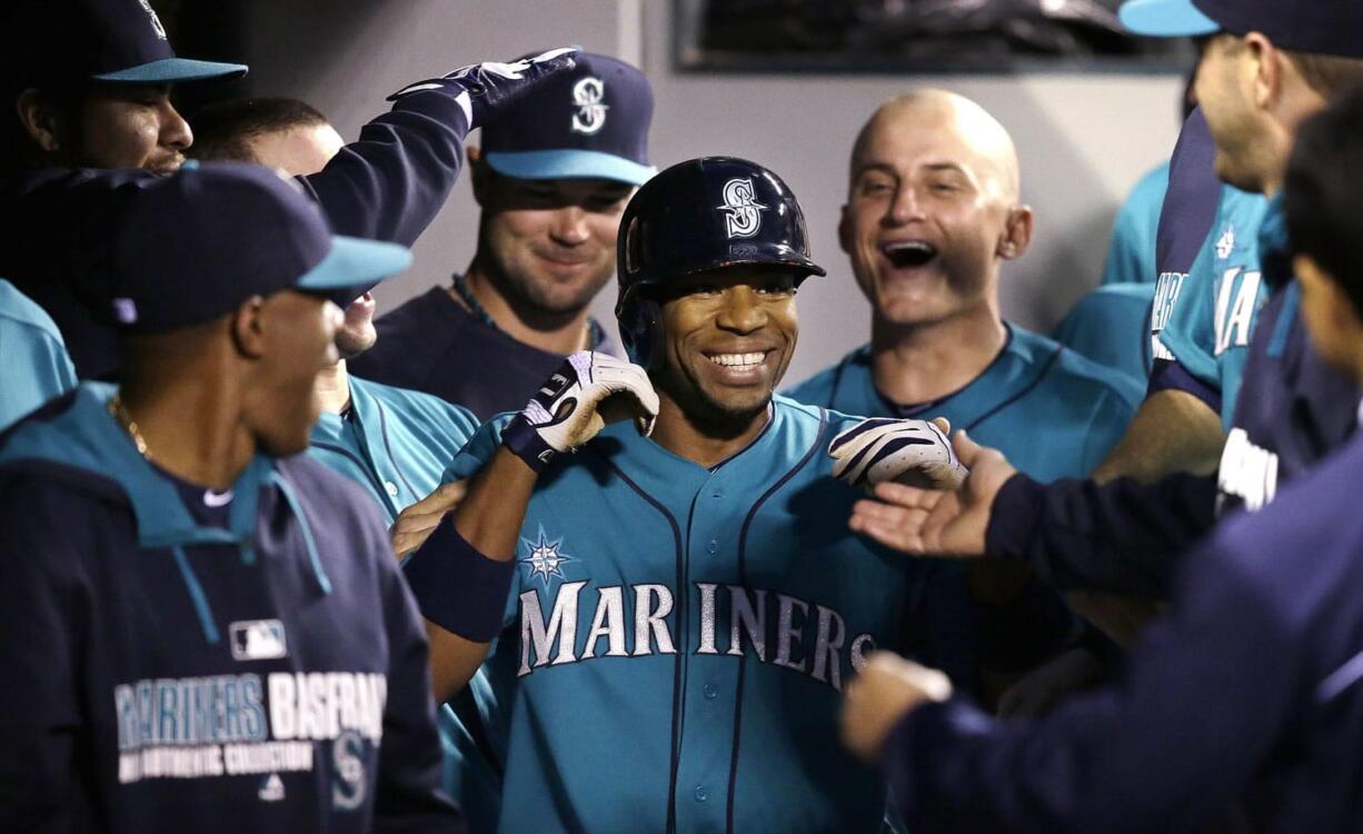 Seattle Mariners' Endy Chavez, center, is congratulated in the dugout after hitting a home run against the Cleveland Indians in the seventh inning of a baseball game Friday, June 27, 2014, in Seattle.