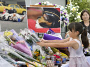 A girl lays bouquets of flowers Sunday at an altar especially set up for a funeral of Tama, a cat stationmaster, in Kinokawa City, Wakayama Prefecture, western Japan.