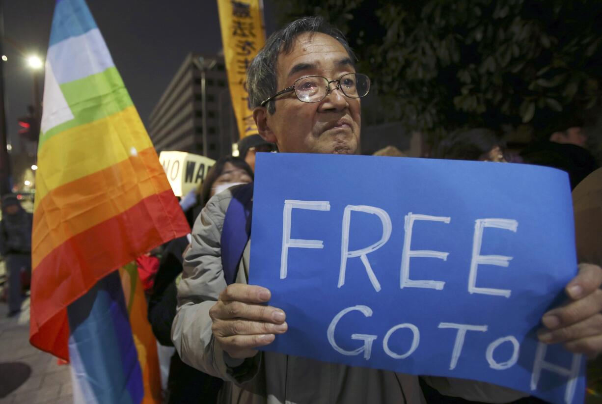 An anti-Prime Minister Shinzo Abe protester attends a rally with a sign in front of Abe's official residence in Tokyo on Sunday.