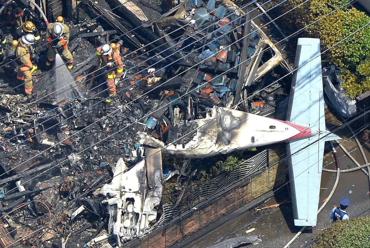 Workers examine the wreckage after a small plane crashes Sunday in the suburbs of Tokyo.