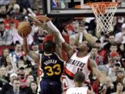 Utah Jazz forward Trevor Booker, left, drives to the basket as Portland Trail Blazers forward LaMarcus Aldridge defends during the first half of an NBA basketball game in Portland, Ore., Tuesday, Feb. 3, 2015.