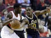 Utah Jazz guard Alec Burks, right, reaches in on Portland Trail Blazers guard Wesley Matthews during the first half of a pre-season NBA basketball game in Portland, Ore., Thursday, Oct.