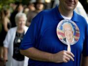 Bill Case, of Columbia, S.C., holds a fan bearing the image of former President Jimmy Carter while waiting in line to enter Maranatha Baptist Church for Sunday School class Sunday in Plains, Ga.