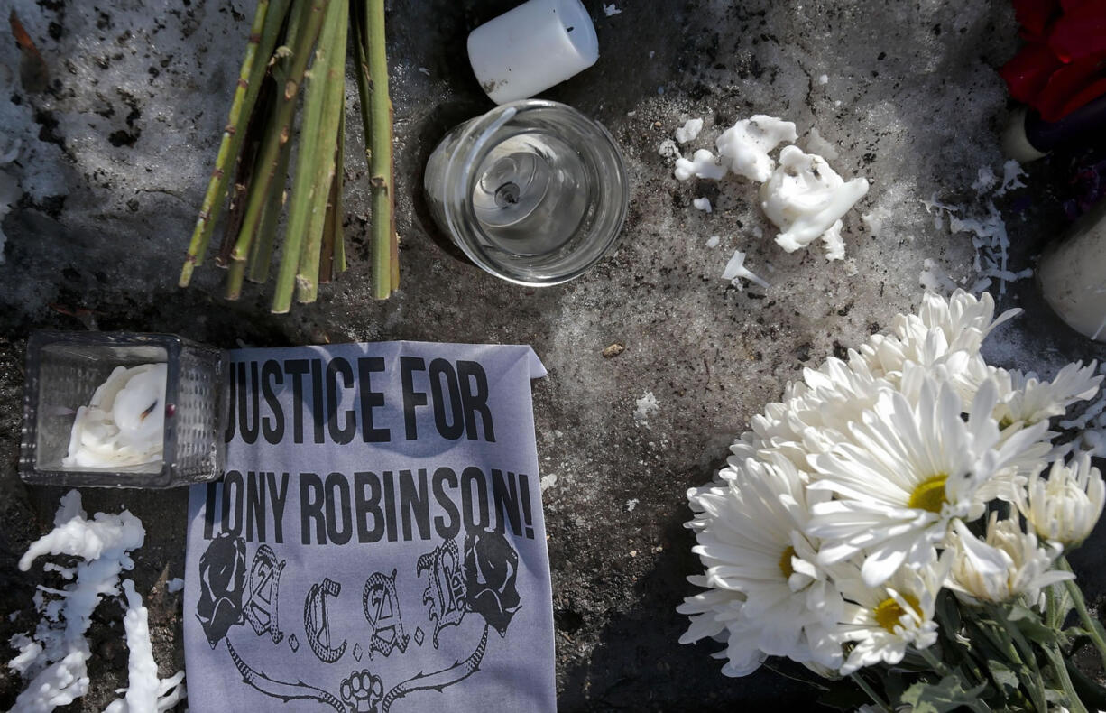 Parts of a memorial rest on a snow bank Tuesday near the apartment house in Madison, Wis., where police officer Matt Kenny shot unarmed 19-year-old Tony Robinson on Friday night.