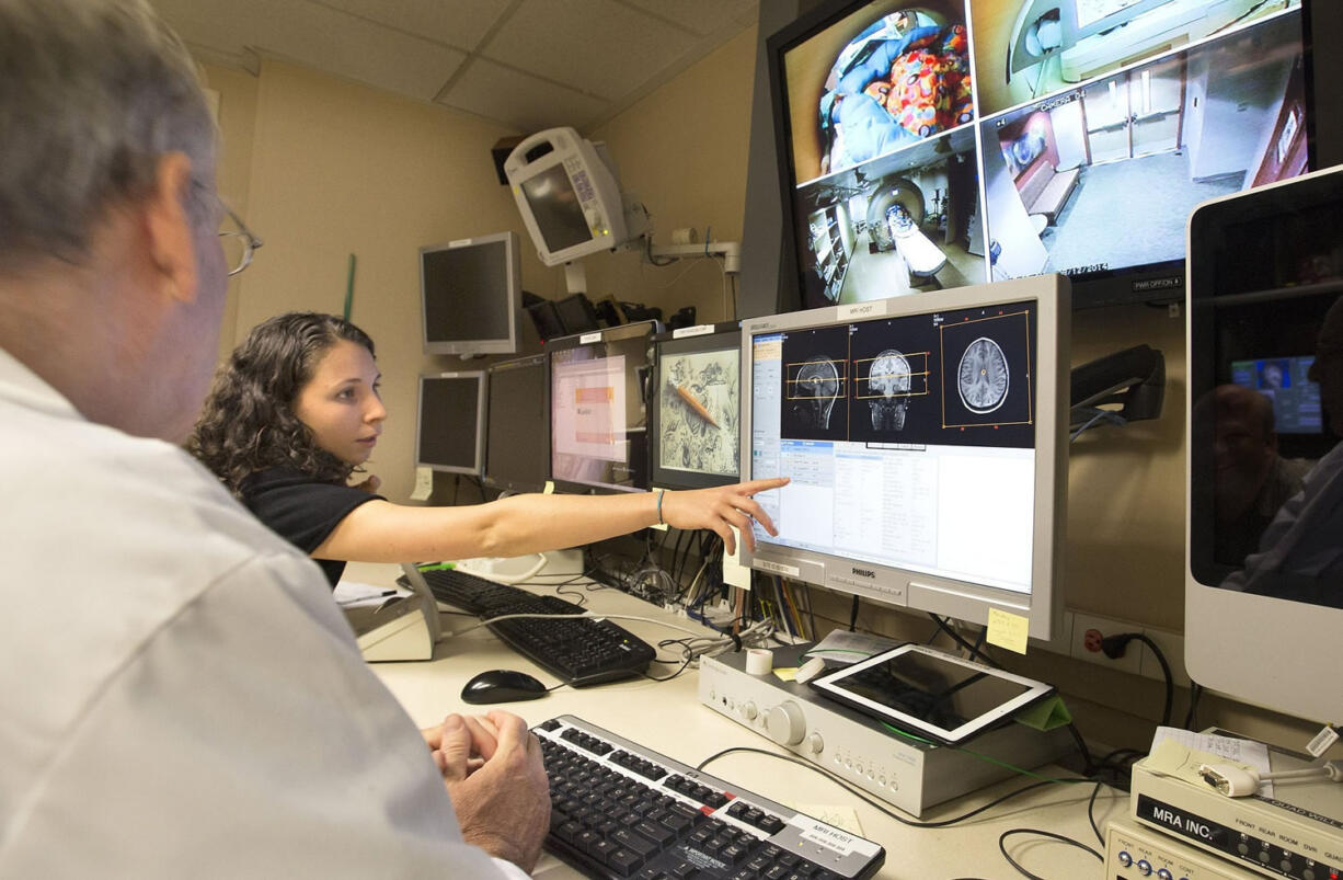 Researcher Zoe Mestre, right, and radiologist Todd Richards examine scans as part of a brain study at the University of Washington in Seattle. Research on a child's brain as they learn to speak, read and write is being done in hopes that treatments can be developed for those who struggle with these skills.