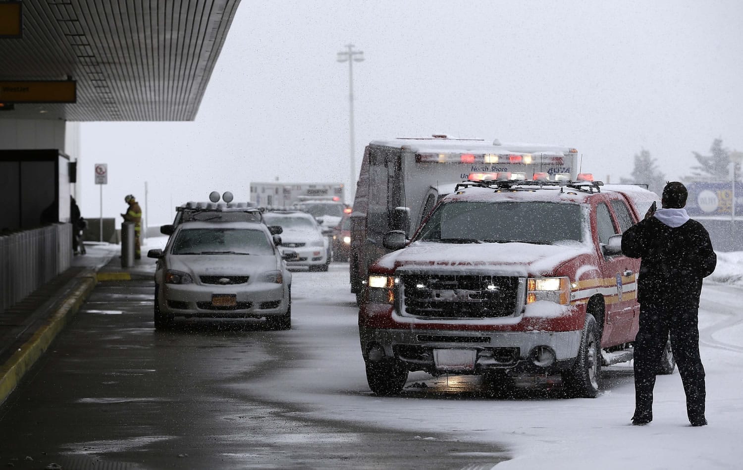 Emergency vehicles line up outside of a terminal at LaGuardia Airport in New York, Thursday, March 5, 2015. A plane from Atlanta skidded off a runway at the airport while landing Thursday, crashing through a chain-link fence and sending passengers saddled with bags and bundled up in heavy coats and scarves sliding down an inflated chute to safety on the snowy pavement.