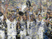 Los Angeles Galaxy's Landon Donovan, center, hoists the trophy as he and teammates celebrate after winning the MLS Cup championship against the New England Revolution on Sunday, Dec. 7, 2014, in Carson, Calif. (AP Photo/Jae C.