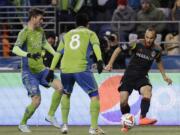 Los Angeles Galaxy's Landon Donovan, right, kicks away from Seattle Sounders' Gonzalo Pineda (8) and Brad Evans, left, in the first half of the second leg of the MLS Western Conference final, Sunday, Nov. 30, 2014, in Seattle. (AP Photo/Ted S.