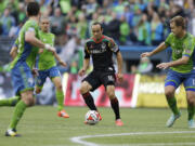 Los Angeles Galaxy midfielder Landon Donovan, center, dribbles the ball as Seattle Sounders' Chad Marshall, right, closes in during the first half Saturday, Oct. 25, 2014, in Seattle. (AP Photo/Ted S.