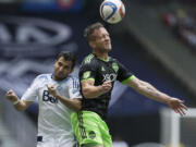 Seattle Sounders' Chad Barrett, right, out-jumps Vancouver Whitecaps' Steven Beitashour to get his head on the ball during the first half in Vancouver, British Columbia, on Saturday, May 16, 2015.