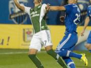 Portland Timbers' Maximiliano Urruti, left, and Montreal Impact's Krzysztof Krol vie for the ball during the first half of an MLS soccer game Sunday, July 27, 2014, in Montreal.