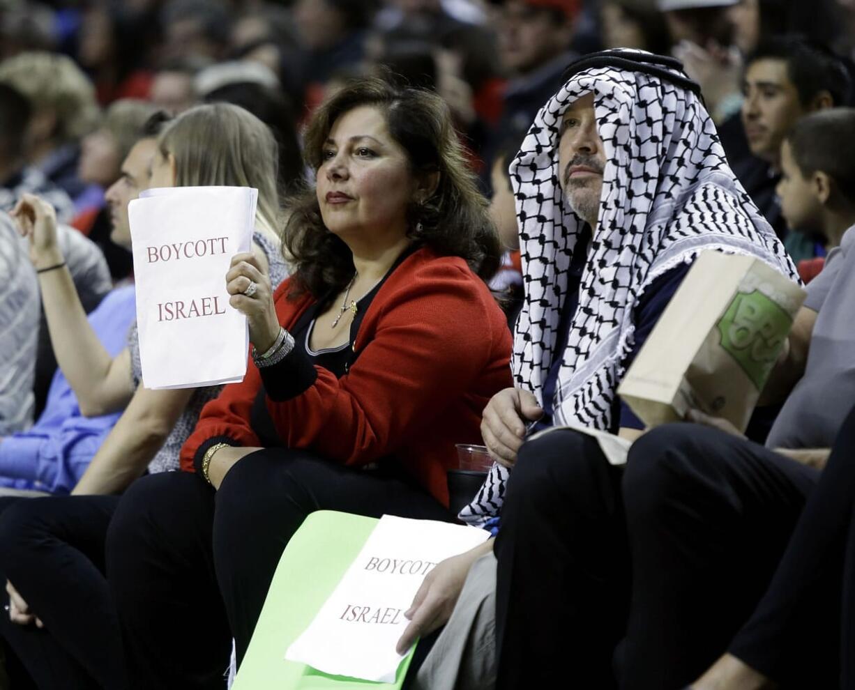 Hala Gores, left, and Joe Finkbonner hold &quot;Boycott Israel&quot; signs from their courtside seats during the Trail Blazers' exhibition game against Maccabi Haifa.