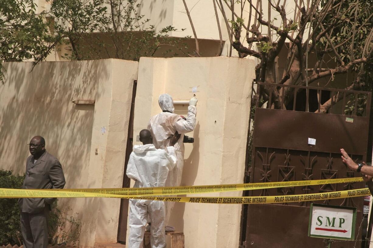 Investigators, center, gather evidence at a nightclub that was attacked by gunmen as armed forces  provide security in Bamako, Mali, Saturday, March 7, 2015. A masked gunman sprayed bullets around a nightclub popular with foreigners in Mali?s capital early Saturday, killing at least five people including a French person and a Belgian national, officials and witnesses said.