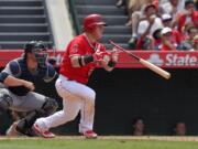 Los Angeles Angels' Kole Calhoun, right, hits an RBI-single as Seattle Mariners catcher Mike Zunino looks on during the eighth inning Sunday, June 28, 2015, in Anaheim, Calif. (AP Photo/Mark J.