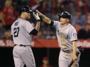 Seattle Mariners' Kyle Seager, right, is greeted by Corey Hart after he scored on a double hit by Logan Morrison during the 12th inning Saturday. (AP Photo/Jae C.