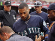 Seattle's Robinson Cano, center, is taken from the bench with a knot on his forehead after an overthrow by the Los Angeles Angels during infield warmups to begin the seventh inning in Anaheim, Calif., Saturday, June 27, 2015. Cano was removed from the game.