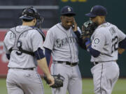 Seattle Mariners pitcher Roenis Elias, center, meets with catcher Mike Zunino (3) and second baseman Robinson Cano (22) during the first inning against the Oakland Athletics in Oakland, Calif., Thursday, July 2, 2015. The Athletics won 4-0.