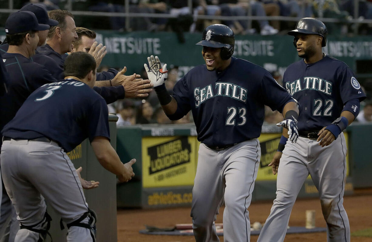 Seattle Mariners' Nelson Cruz (23) celebrates with teammates after hitting a two-run home run that scored Robinson Cano (22) during the eighth inning against the Oakland Athletics in Oakland, Calif., Friday, July 3, 2015.