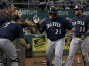 Seattle Mariners' Nelson Cruz (23) celebrates with teammates after hitting a two-run home run that scored Robinson Cano (22) during the eighth inning against the Oakland Athletics in Oakland, Calif., Friday, July 3, 2015.