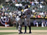 Seattle Mariners' Felix Hernandez (34) and Jesus Sucre speak on the mound in the third inning against the Oakland Athletics on Saturday, July 4, 2015, in Oakland, Calif.