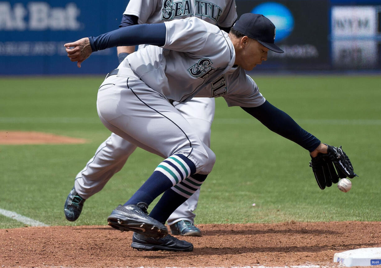 Seattle Mariners starting pitcher Taijuan Walker bobbles the ball but manages to recover and force out Toronto Blue Jays shortstop Ryan Goins at first base during the third inning Sunday, May 24, 2015, in Toronto.