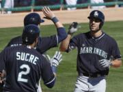 Seattle Mariners' Chris Taylor, right, is congratulated by teammates Jesus Sucre (2) and Shawn O'Malley as Taylor crosses home plate after hitting a home run in the fifth inning of a spring training game against Los Angeles Dodgers, on Friday, March 6, 2015, in Phoenix.