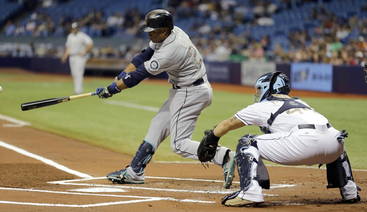 Seattle Mariners' Robinson Cano, left, lines an RBI single off Tampa Bay Rays starting pitcher Jake Odorizzi during the first inning Monday, May 25, 2015, in St. Petersburg, Fla. Mariners' Seth Smith scored on the hit.