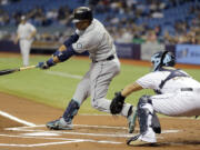 Seattle Mariners' Robinson Cano, left, lines an RBI single off Tampa Bay Rays starting pitcher Jake Odorizzi during the first inning Monday, May 25, 2015, in St. Petersburg, Fla. Mariners' Seth Smith scored on the hit.