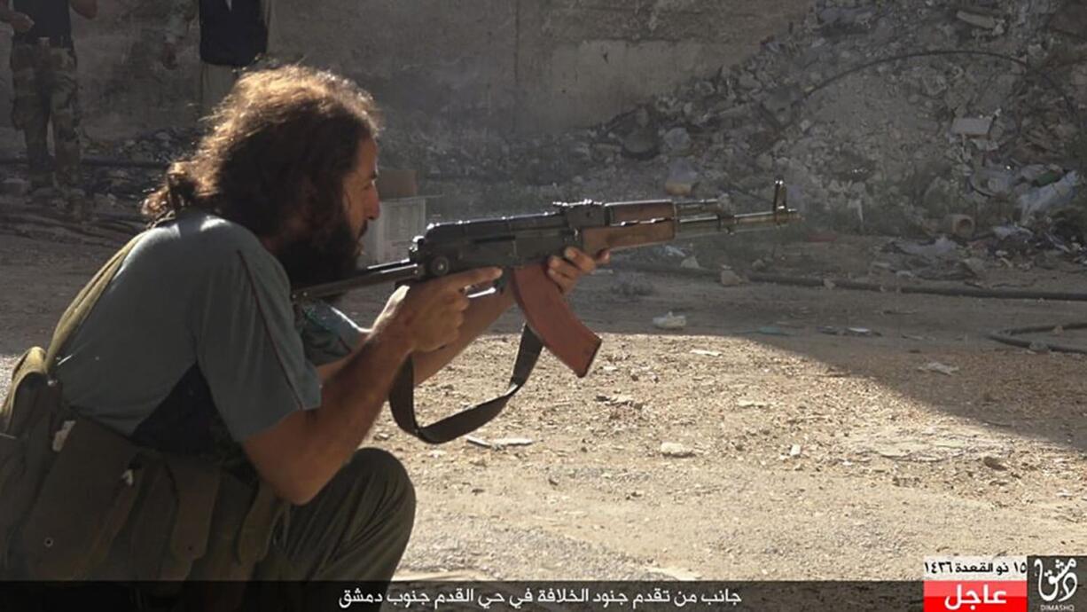 In this picture released Sunday, August 30, 2015 by the Rased News Network, a Facebook page affiliated with the Islamic State group, an Islamic State militant takes his position in an alley, in the Qadam neighborhood of Damascus, Syria. Islamic State fighters on Sunday pushed into Qadam, a large district in southern Damascus, clashing with rival militants just a few kilometers from the center of the Syrian capital, the extremist group and Syrian activists said.