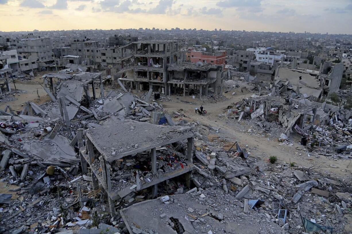 Palestinians sit between the rubble of their destroyed building in Shijaiyah, neighborhood of Gaza City, in the northern Gaza Strip. Delegates representing some 50 nations and 20 regional and international organizations attended a donor conference in Cairo, Egypt, on Sunday to help Gaza rebuild after the war between Israel and Gaza's militant Islamic group Hamas this summer. Organizers of the Cairo conference hope pledges of over 5 billion dollars will be paid over the period of three years to aid reconstruction in the Gaza Strip, which borders Israel and Egypt.