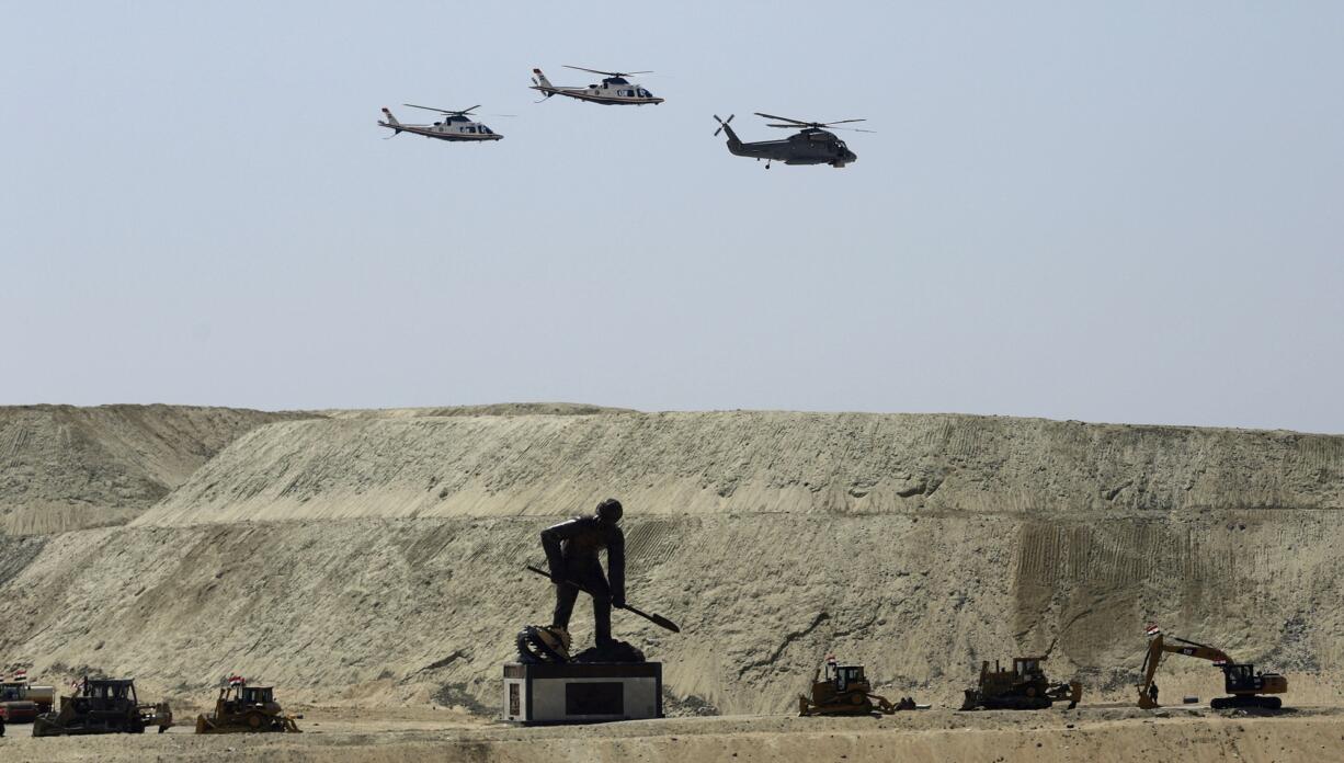 Egyptian air force planes parade over a statue representing a man digging the new section of the Suez Canal in Ismailia, Egypt, on Thursday.