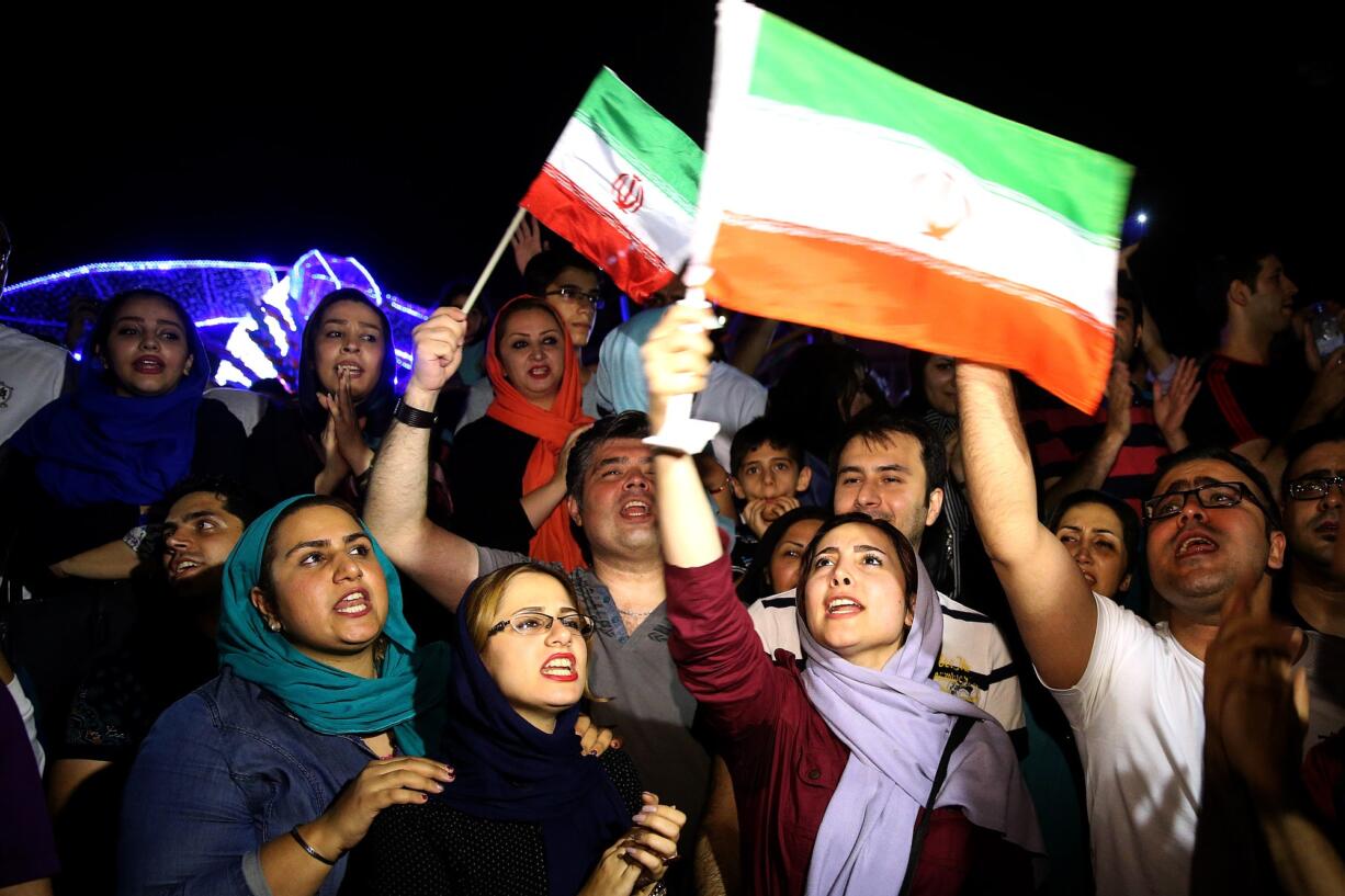 Jubilant Iranians sing and wave Iran flags during street celebrations following a landmark nuclear deal, in Tehran, Iran, Tuesday, July 14, 2015. After long, fractious negotiations, world powers and Iran struck an historic deal Tuesday to curb Iran's nuclear program in exchange for billions of dollars in relief from international sanctions - an agreement aimed at averting the threat of a nuclear-armed Iran and another U.S. military intervention in the Middle East.