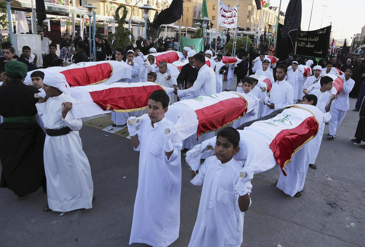 Shiite Muslim worshippers carry symbolic coffins for victims of the Islamic State group Sunday near the holy shrine of Imam Hussein ahead of the Ashoura holiday in the Shiite holy city of Karbala, 50 miles south of Baghdad, Iraq.