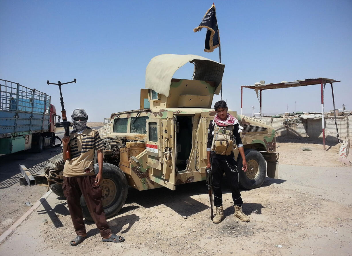 FILE - In this file photo taken Thursday, June 19, 2014, al-Qaeda-inspired militants stand with captured Iraqi army Humvee at a checkpoint outside an oil refinery in Beiji, some 250 kilometers (155 miles) north of Baghdad, Iraq. The government forces on Friday, Nov. 14, drove Islamic State militants out from their remaining strongholds inside the oil refinery town of Beiji, two security official said, in a key victory over the terror group that has captured much of northern and western Iraq in a stunning summer offensive.