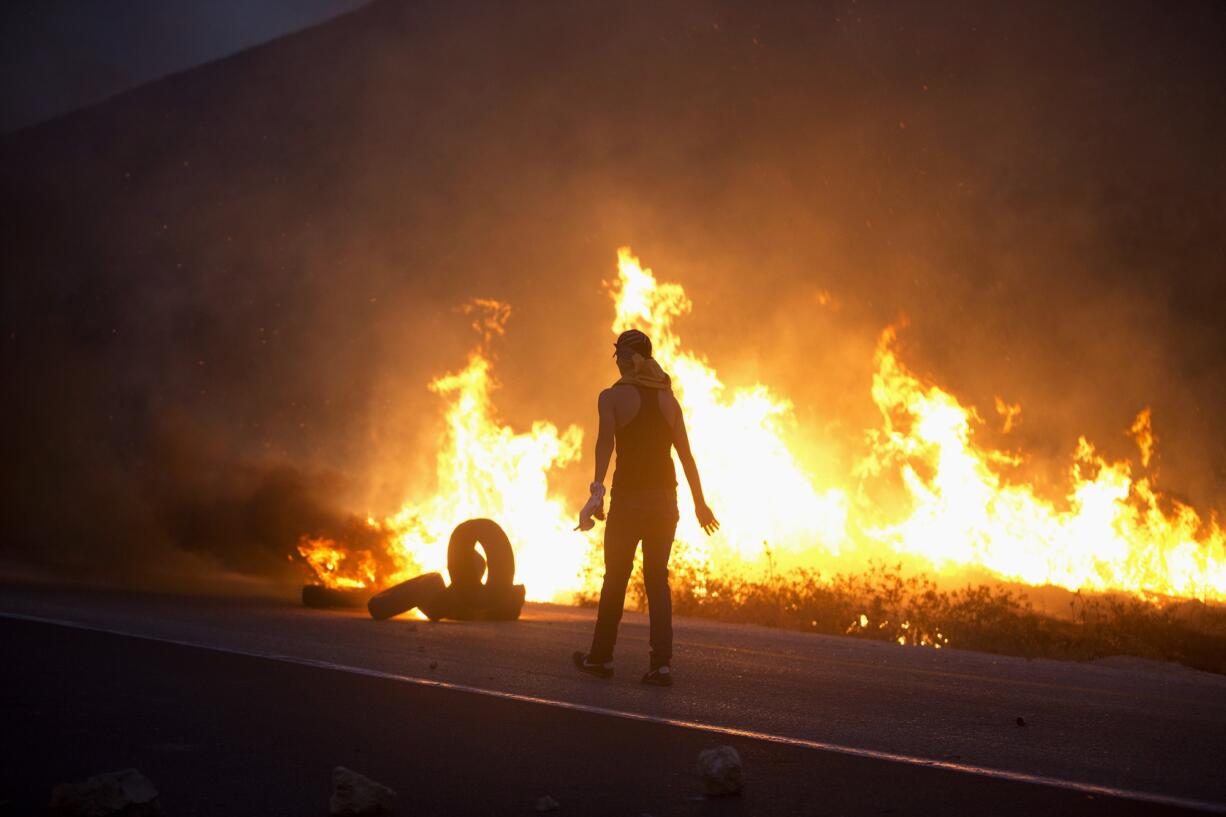 A Palestinian demonstrator burns tires in clashes with Israeli soldiers Sunday near the West Bank city of Nablus.