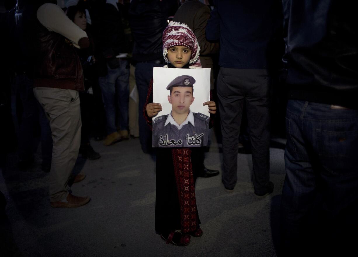 A Jordanian child holds a poster with a picture of Jordanian pilot, Lt. Muath al-Kaseasbeh, who is held by the Islamic State group militants, with Arabic that reads, &quot;we are all Muath,&quot; during a candle vigil in support of Japan, in front of the Japanese embassy, in Amman, Jordan, on Monday.