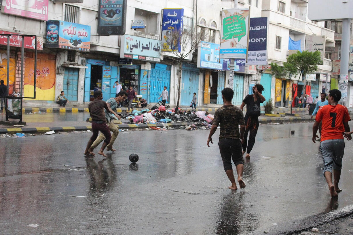 Yemen youths play soccer in the rain on a street in Taiz city, Yemen, on Sunday.