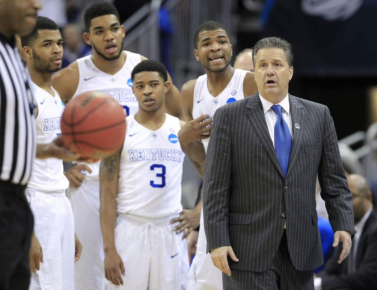 Kentucky guard Aaron Harrison, second from right, and head coach John Calipari listen to the official's explanation of a technical foul called on Harrison during the second half of an NCAA tournament college basketball game against Cincinnati in Louisville, Ky., Saturday, March 21, 2015. Kentucky won the game 64-51.
