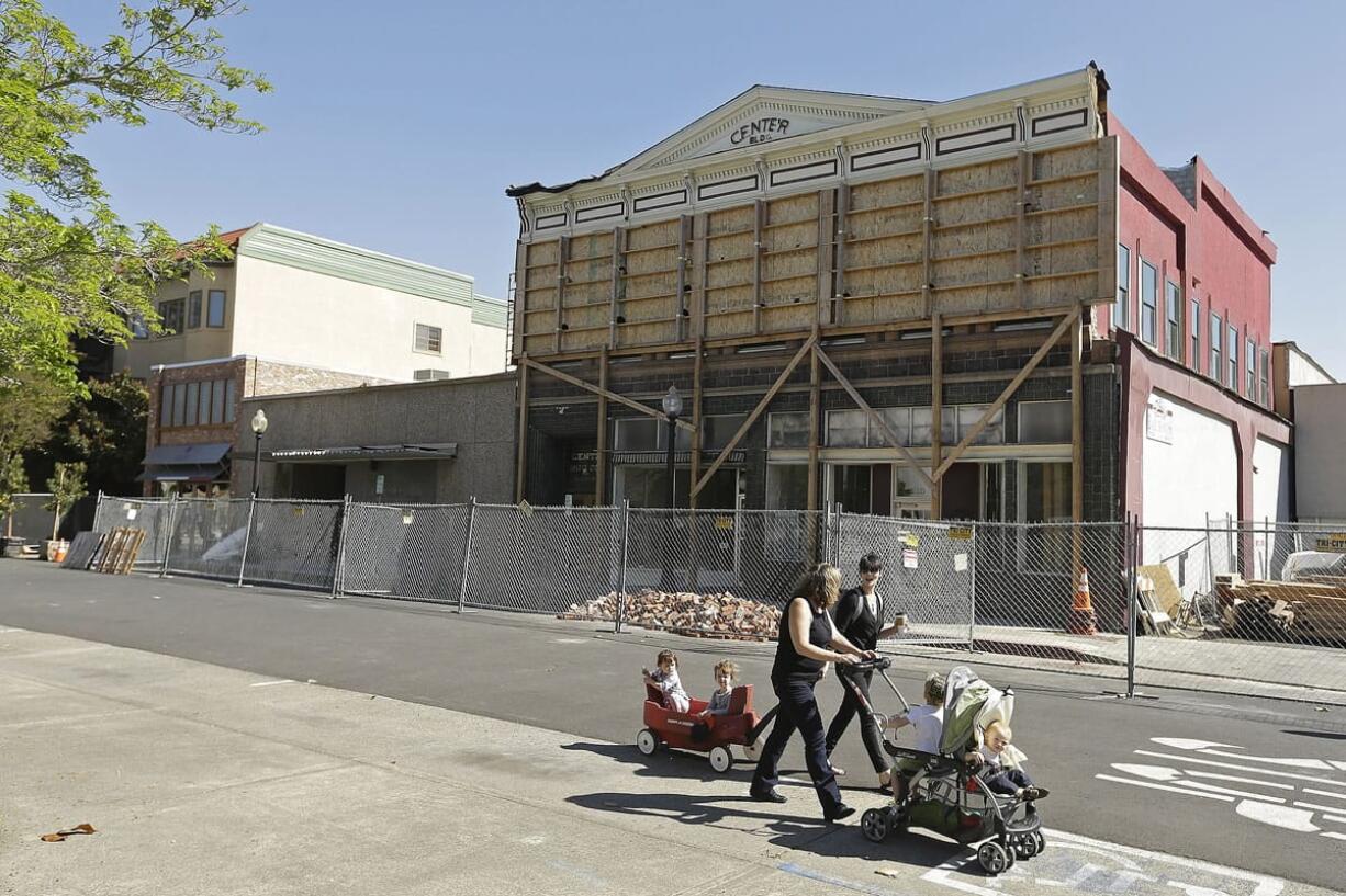 Two women walk with their children past a number of earthquake-damaged buildings in Napa, Calif. One cafe remains open in the middle of the street as the other structures undergo repairs. Recovery continues a year later from the 6.0 Napa earthquake that struck at 3:20 a.m. Aug.