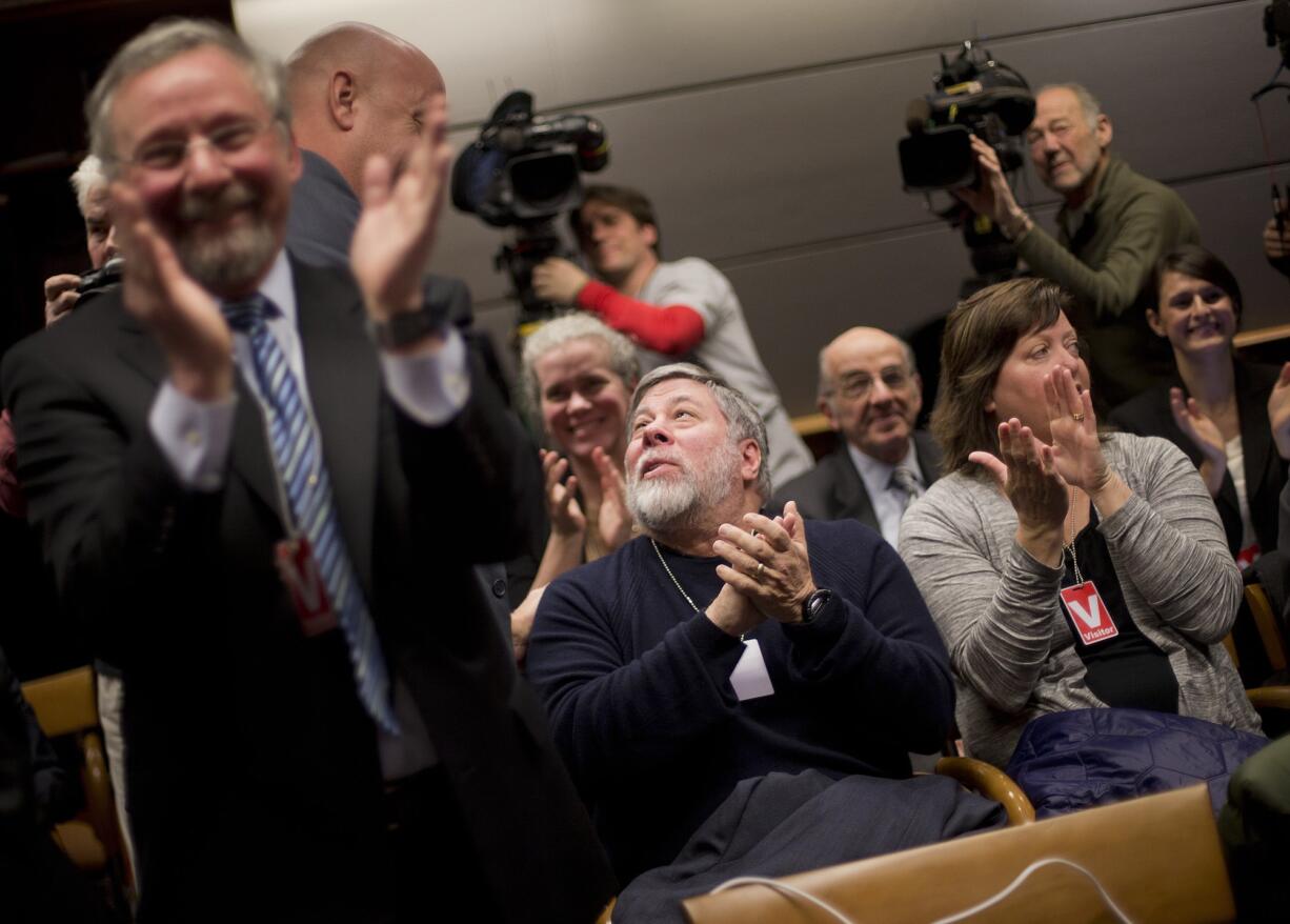 Apple co-founder Steve Wozniak, center, and his wife Janet Hill, right, joins members of the audience in applauding at an open hearing at the Federal Communications Commission in Washington on Thursday.