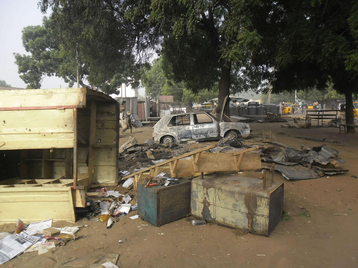 A child, at rear, walks through the scene of an explosion in a mobile phone market in Potiskum, Nigeria, on Monday.