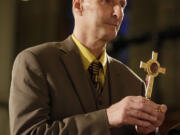 Michael Mencer holds a cross with a lock of hair of the Sister Miriam Teresa Demjanovich during a beatification ceremony for the nun at Cathedral Basilica of the Sacred Heart, Saturday, Oct. 4, 2014, in Newark, N.J. Demjanovich, who died in 1927 at age 26, is credited with curing Mencer's eye disease as a boy when he was given a lock of the nun's hair and prayed to her. The ceremony moves Demjanovich a step closer to sainthood with her beatification as it is the third in a four-step process.